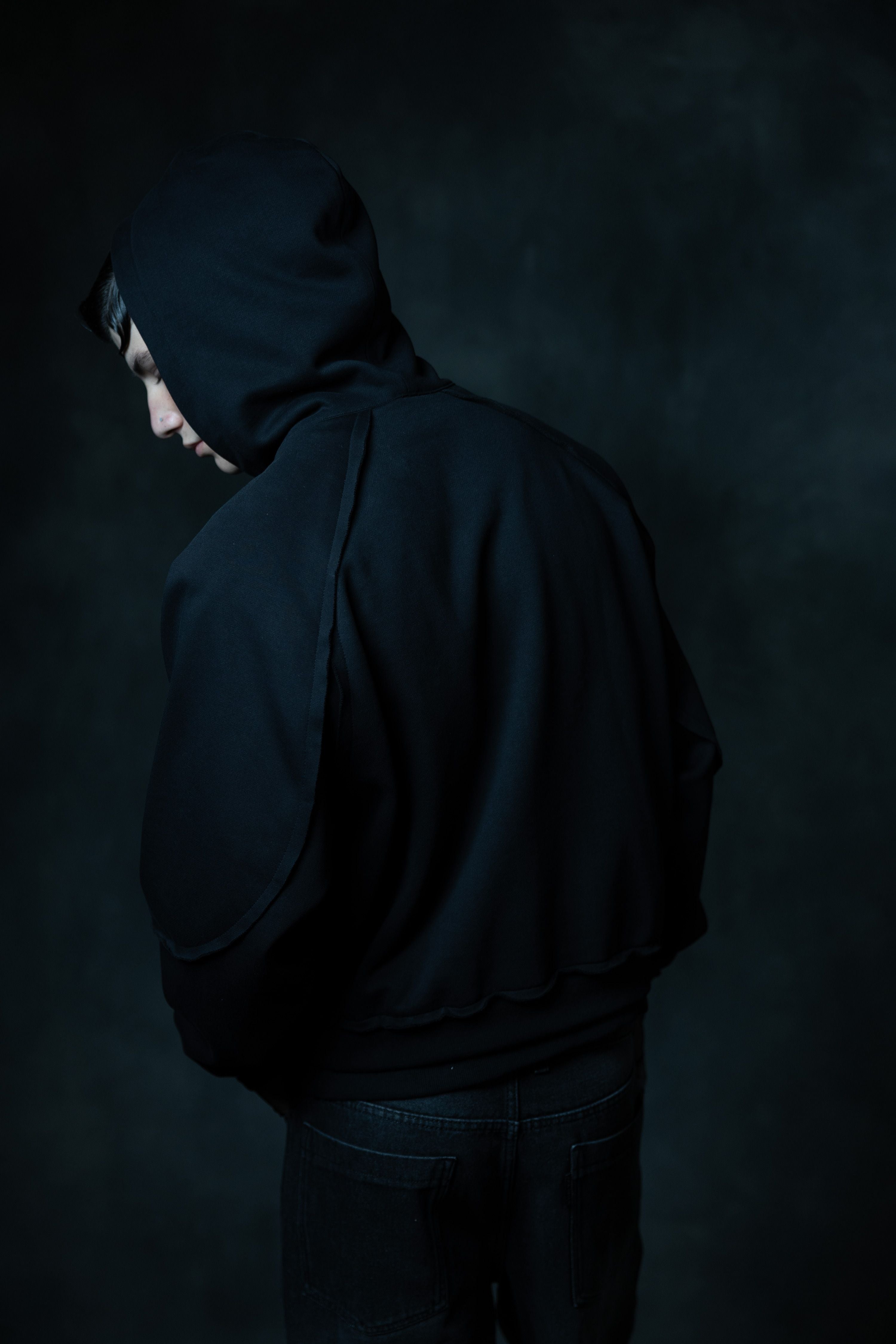 Back view of premium black zip neck hoodie featuring raw edge detailing and minimal urban streetwear design