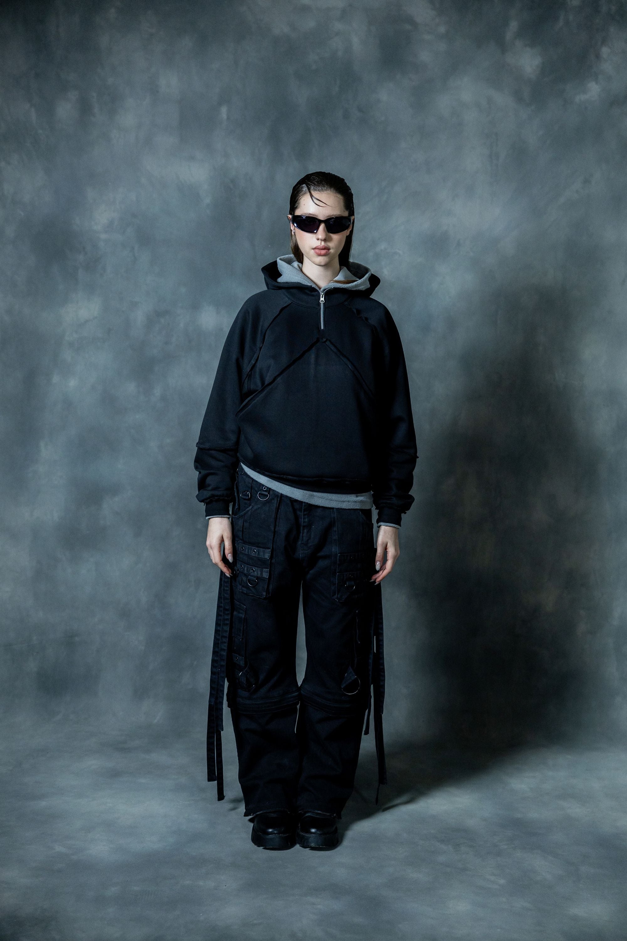Full body view of woman wearing black zip neck hoodie with relaxed fit in modern streetwear style