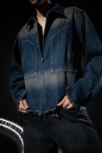 Close-up of a blue denim jacket with zipper closure and frayed edges, highlighting modern streetwear design