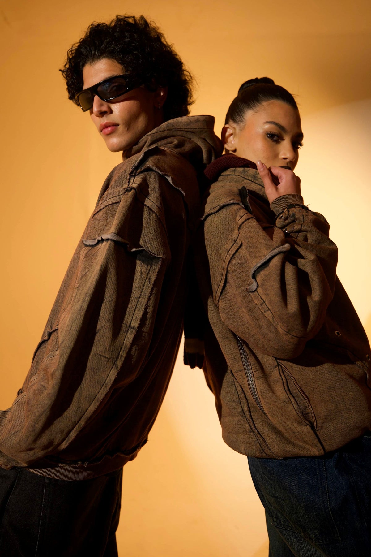 Brown cotton fleece hoodie with raw edge detailing, paired with relaxed fit pants for a streetwear look