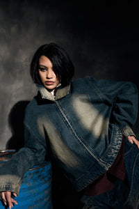 Angled view of denim jacket highlighting fabric texture and structural design