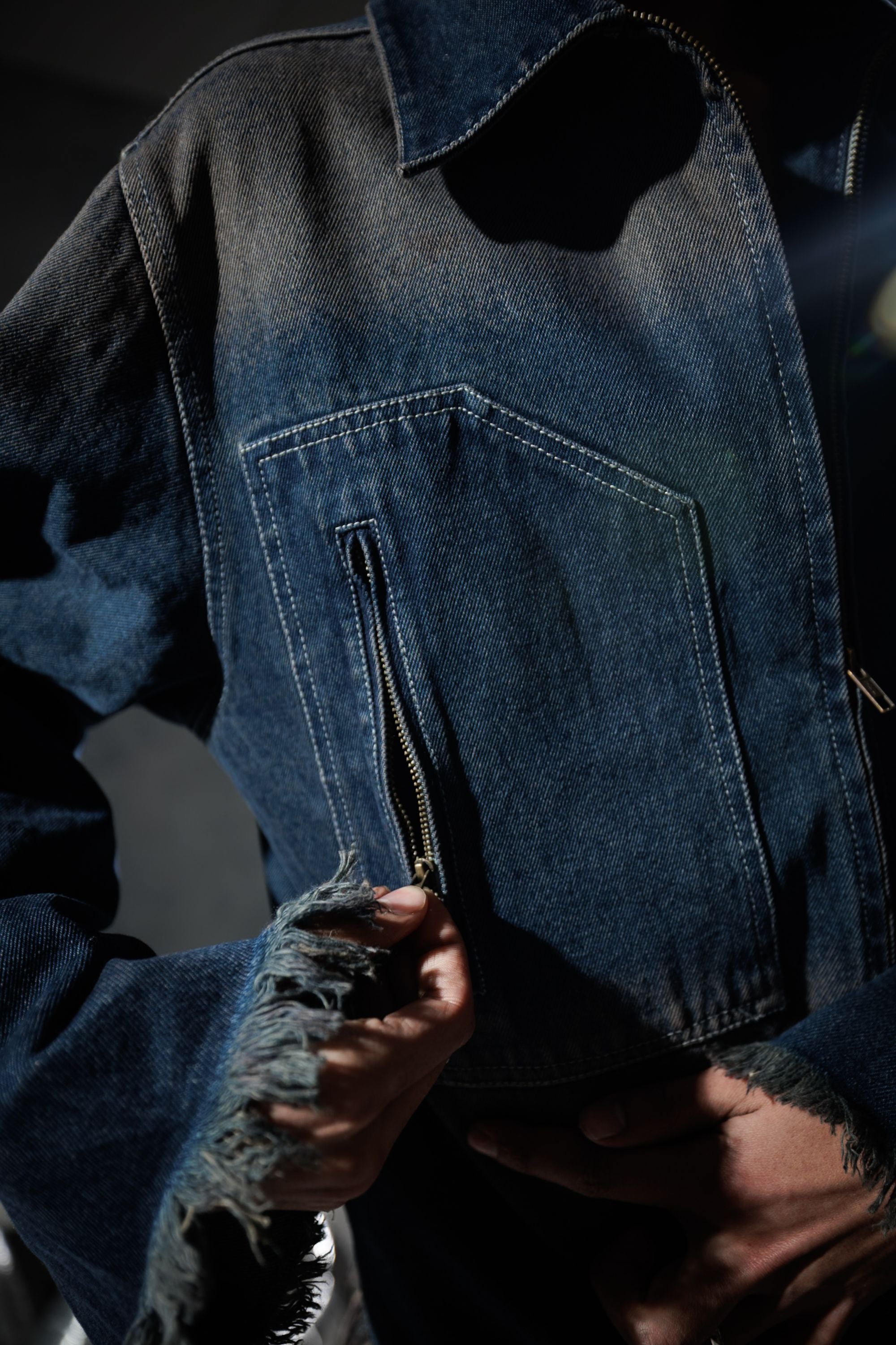 Angled view of blue denim jacket with zipper, highlighting a modern streetwear design