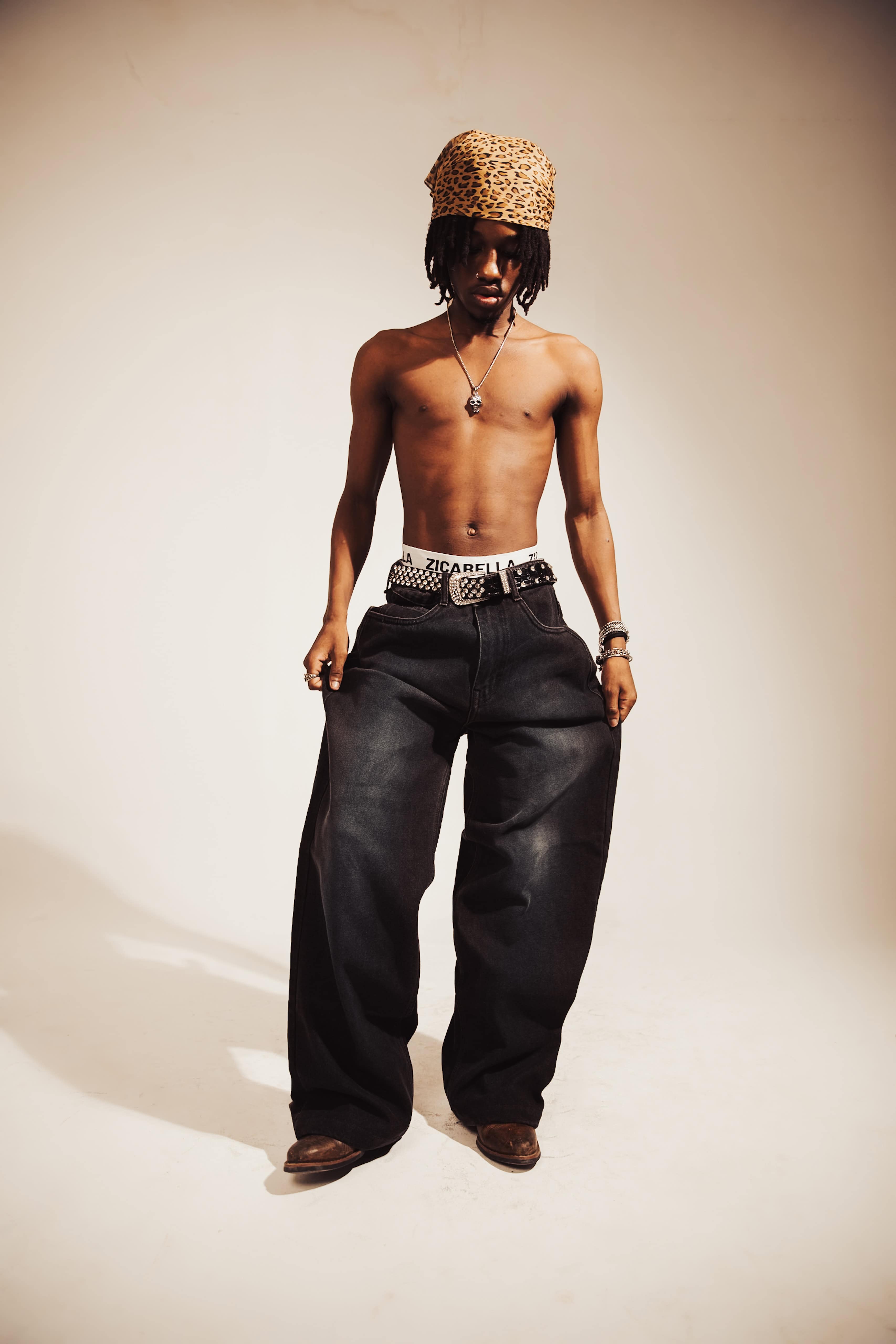 Textured black denim jeans with a baggy fit and strong distressed elements, ideal for high-impact streetwear fashion