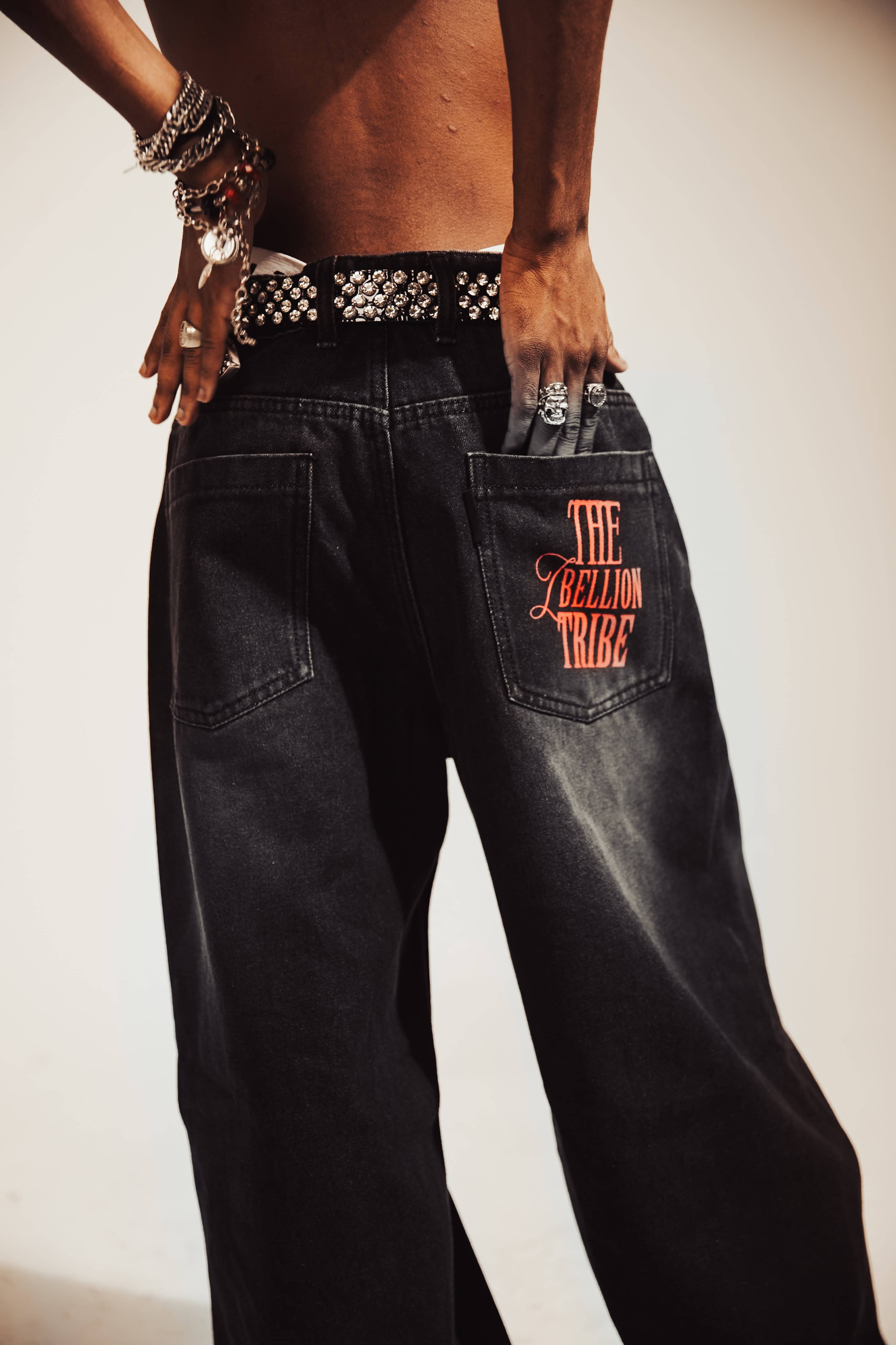 Black denim jeans with a relaxed fit, featuring a washed-black finish and distressed detailing for an urban streetwear look