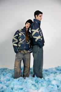 Couple wearing matching premium blue embossed leather jackets with beige appliqué designs, styled for a modern streetwear look