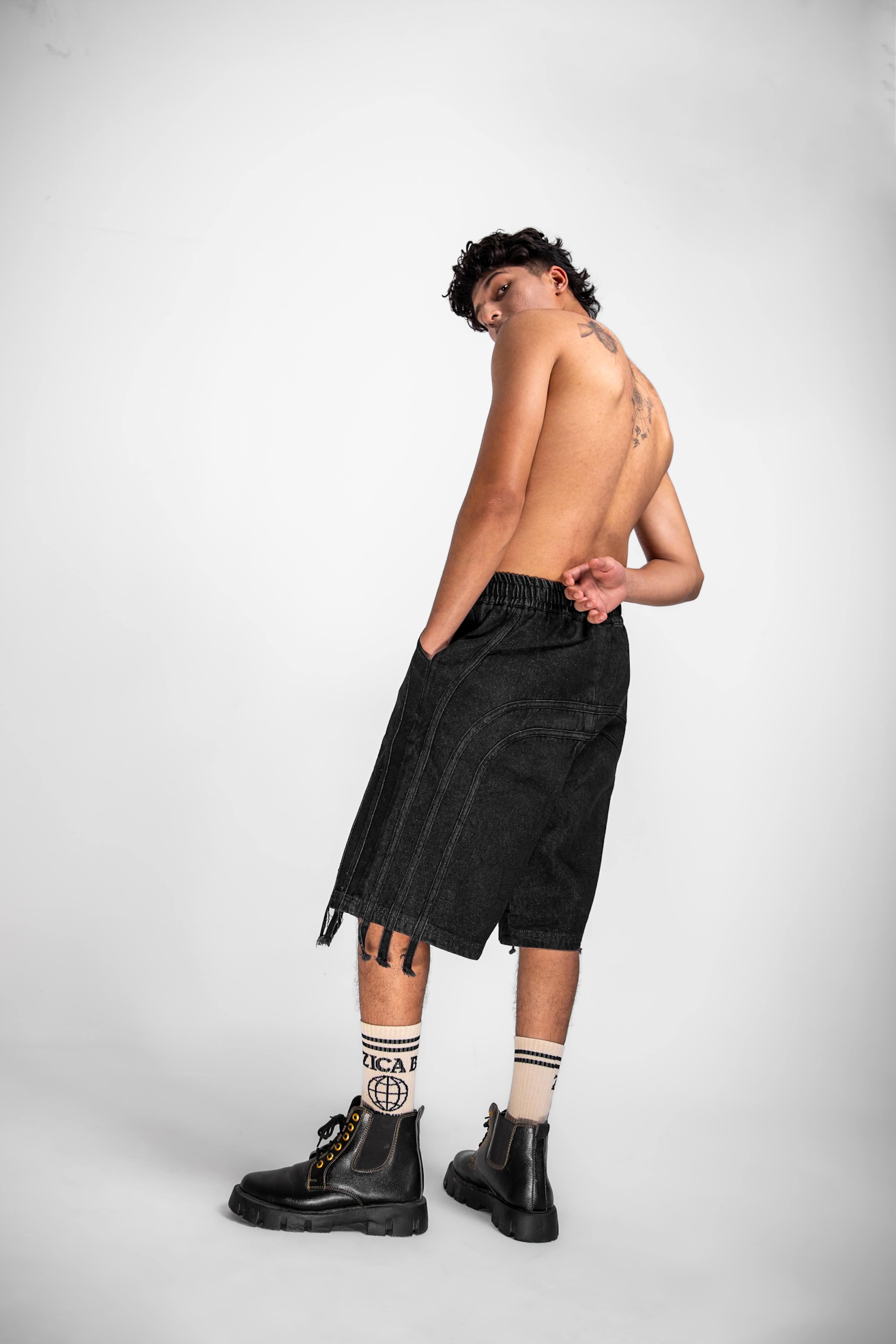 Model showcasing jorts, a mens streetwear essential with fringe accents