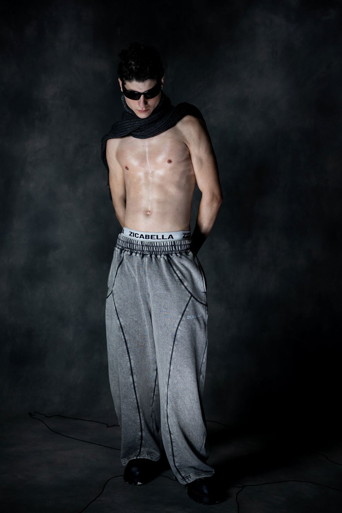 Oversized grey baggy lower styled in dark studio setup with bold streetwear aesthetic