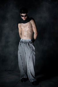 Oversized grey baggy lower styled in dark studio setup with bold streetwear aesthetic